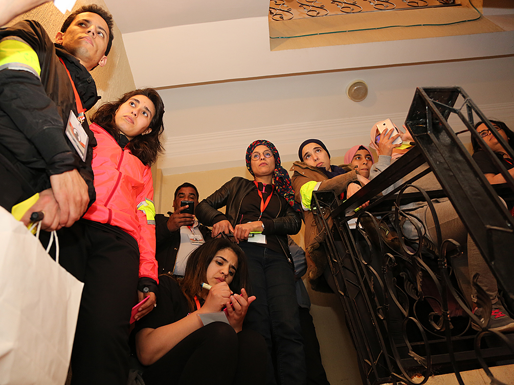 Eine Gruppe von jungen Teilnehmern mit konzentrierten Blicken steht im Treppenhaus