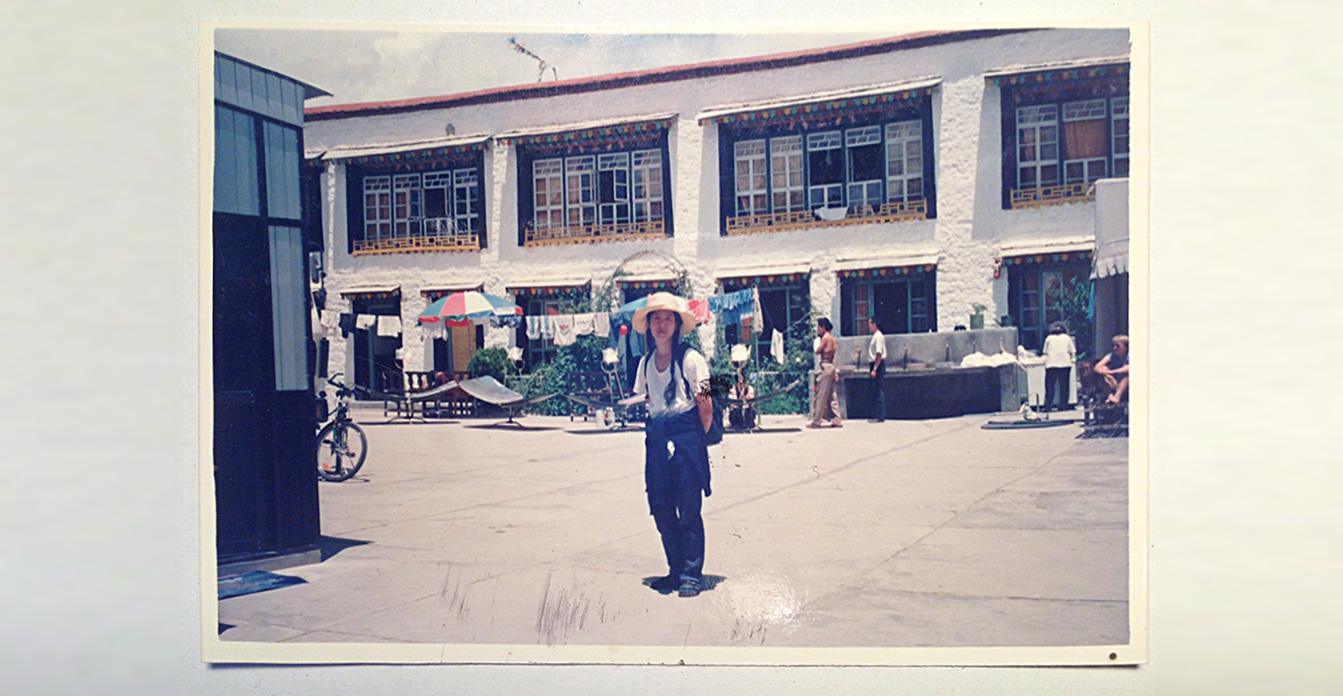 Ein altes, verblichenes Foto zeigt Shau Chung Shin, die im Hof eines Hostels in Lhasa, der Hauptstadt Tibets, steht. Die Sonne steht hoch, die Schatten sind klein. Sie trägt einen Strohhut, ein weißes T-Shirt und lange Zöpfe. Sie hat die Arme hinter ihrem Rücken verschränkt.