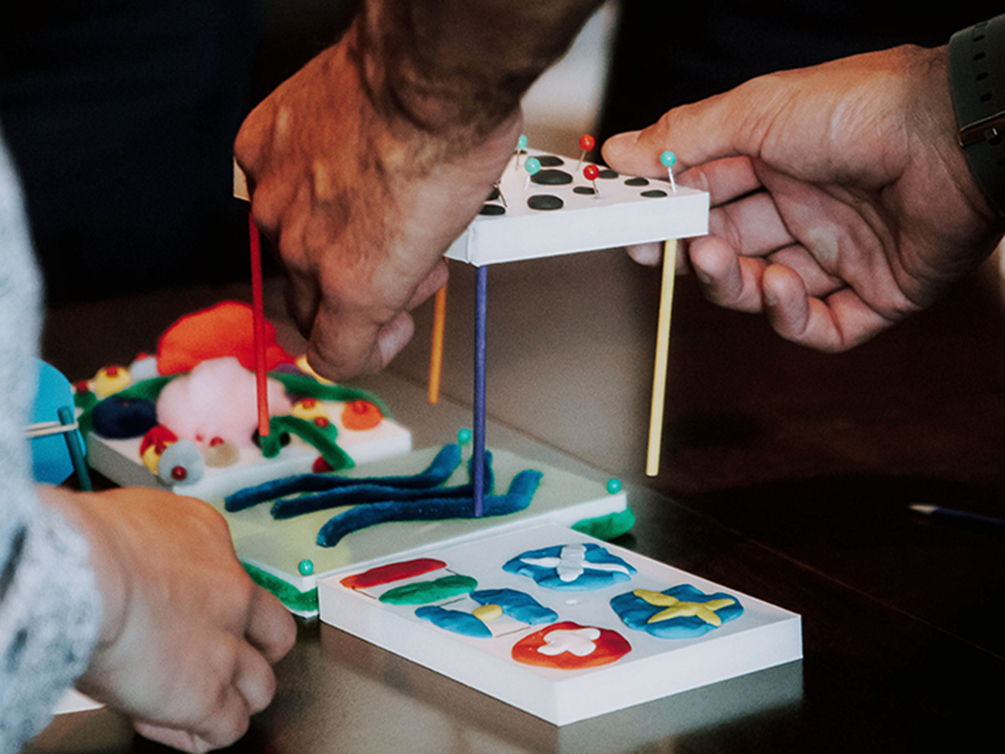 Zwei Hände halten ein Modell, um es mit einem anderen Modell zu verbinden.