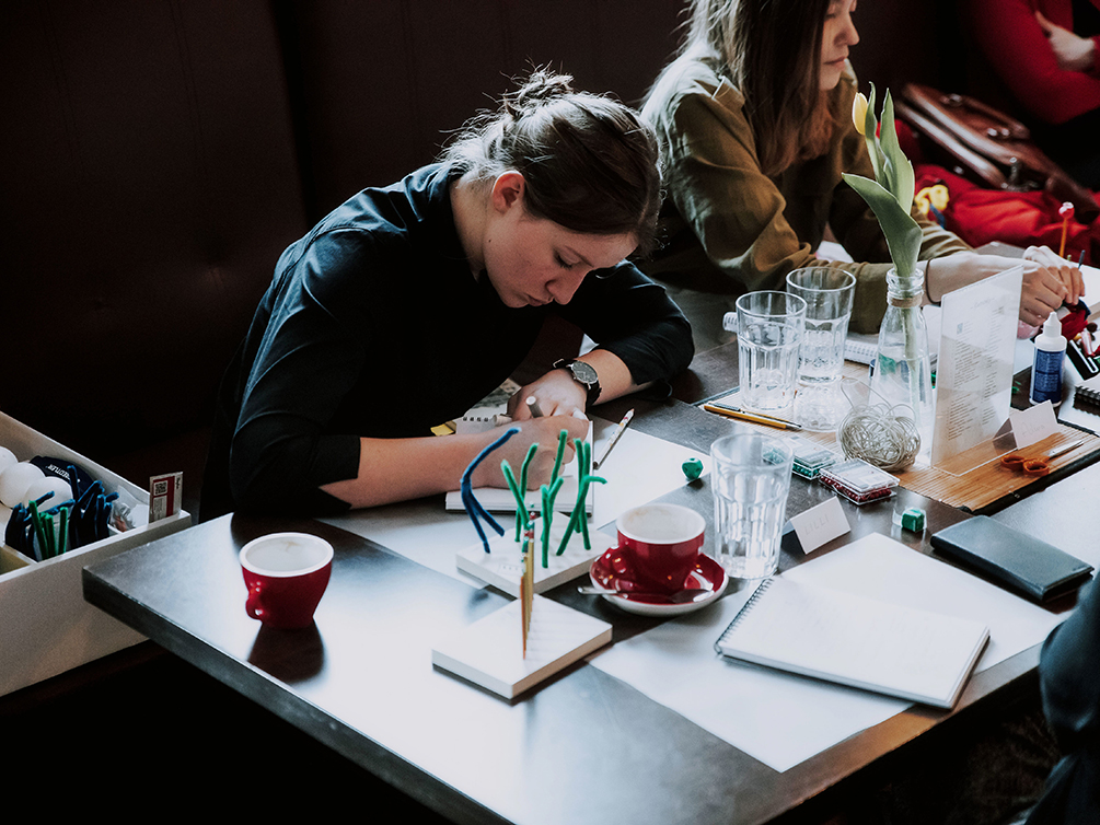 Eine Workshop-Teilnehmerin sitzt am Tisch und schreibt in einen Block.