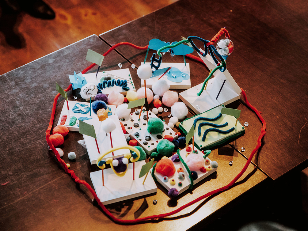 Ein Gefüge aus mehreren bunten Modellen, die zusammengelegt wurden und von einem Kreis aus roten Pfeifenreinigern umgeben sind.