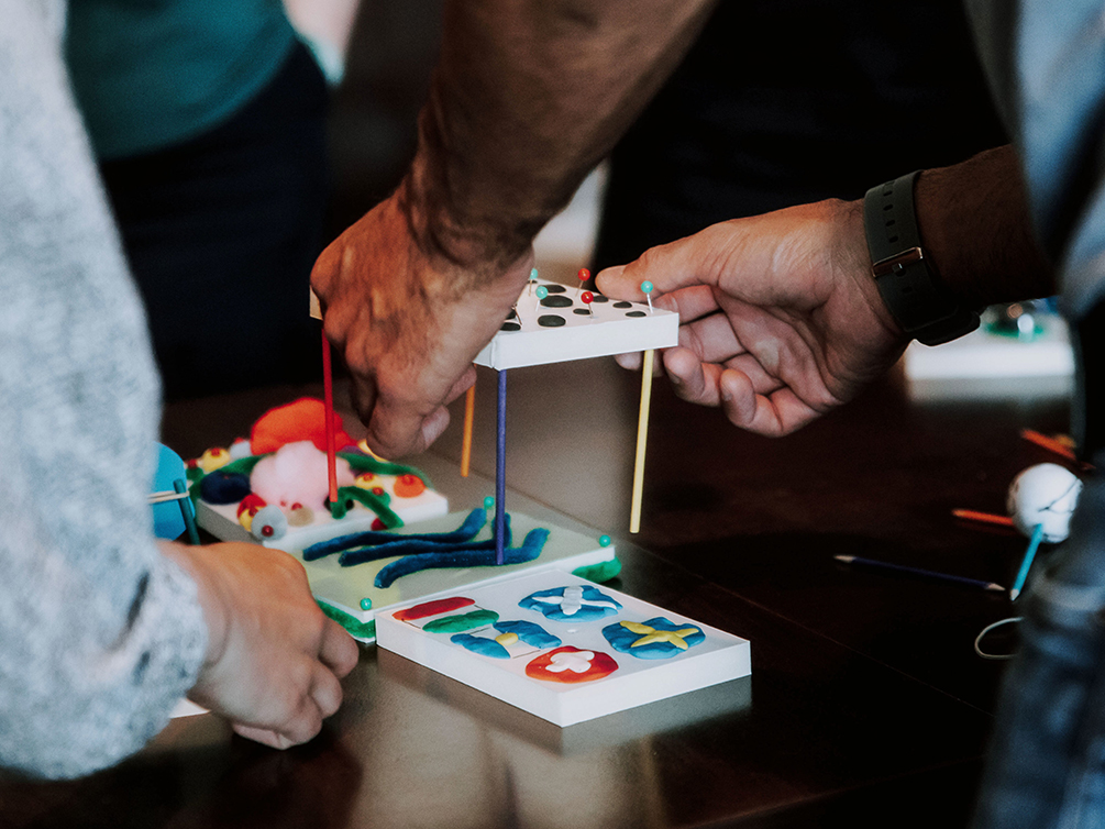 Zwei Hände halten ein Modell, um es mit einem anderen Modell zu verbinden.