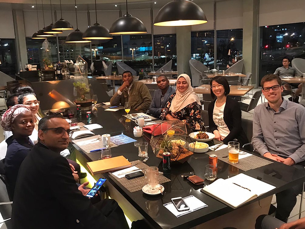 Ein Gruppenbild mit 10 jungen Menschen, die in einem Hotel um einen langen Tisch sitzen.